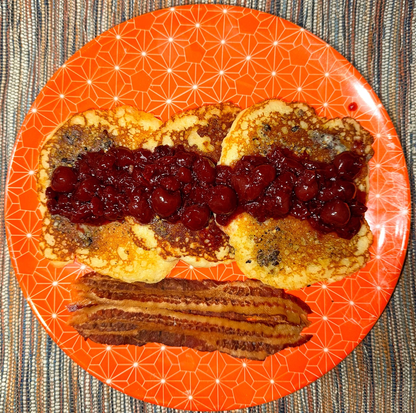 Robert’s labneh pancakes with sour cherry compote and za’atar butter on an orange plate